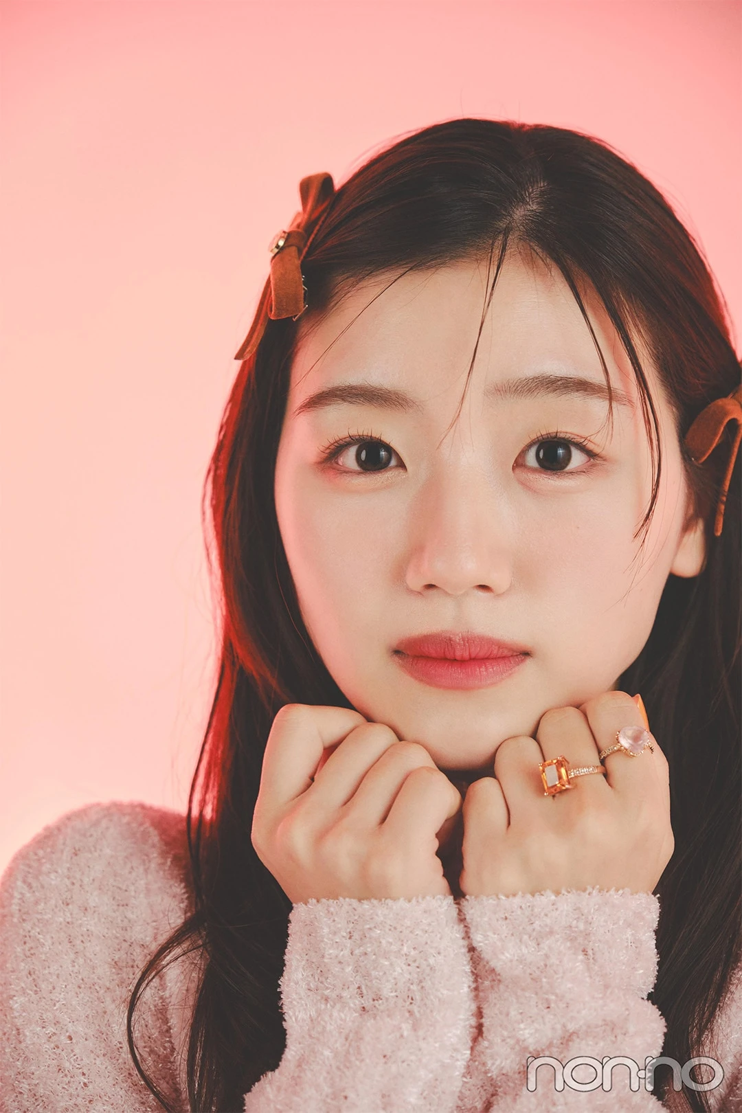 ピンクのニットを着て顎の下に手を添える佐々木美玲