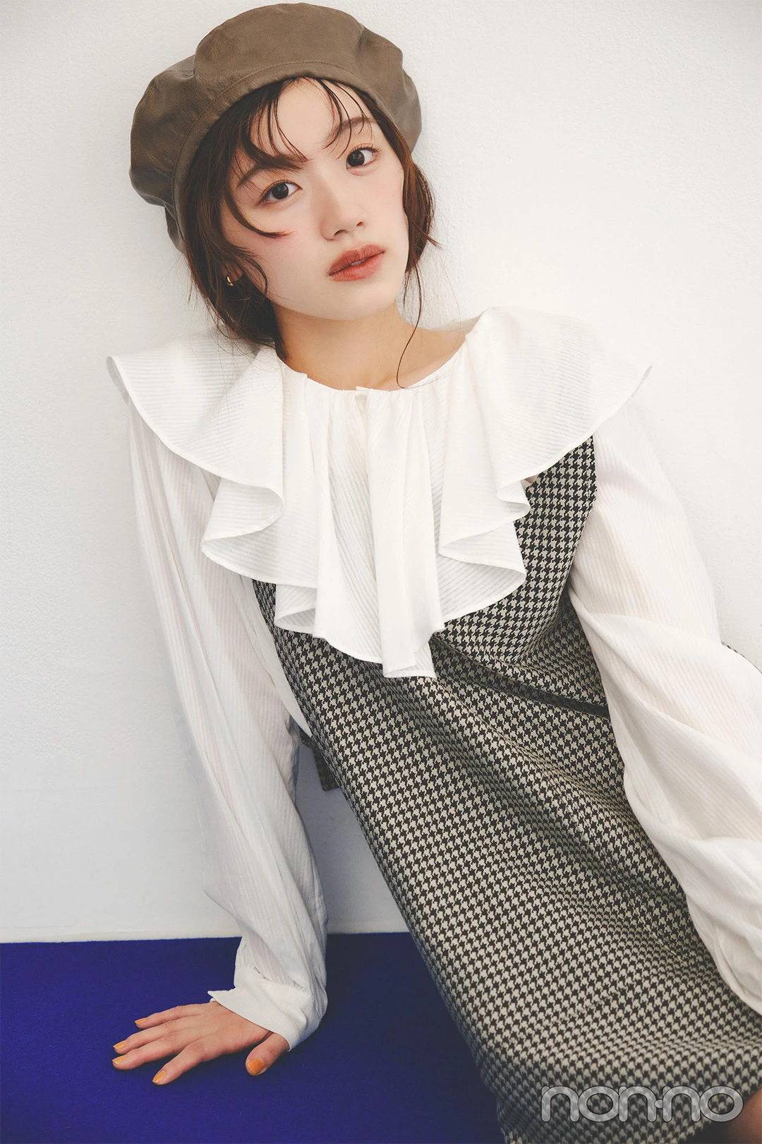チェックのワンピースにベレー帽をかぶって座る佐々木美玲