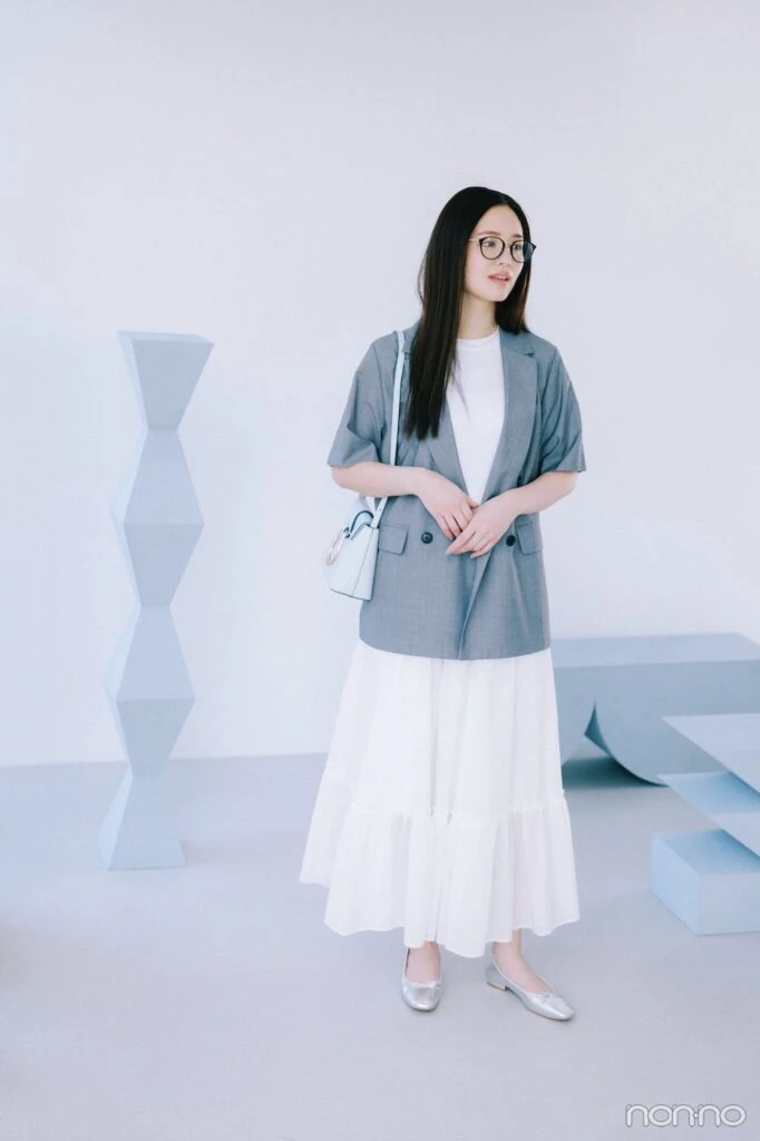 グレージャケットに白いスカートの横田真悠